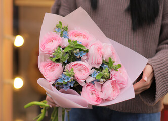 Colorful flowers assorted bouquet of oxypetalum and ranunculus in pink paper. Holiday celebration concept. Bouquet of beautiful flowers in hands. Colorful flowers bouquet wrapped in paper