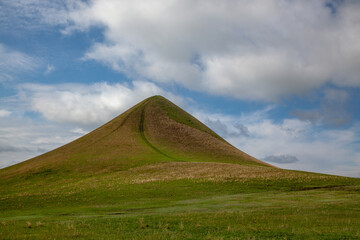 A solitary mountain covered with young, green grass. A country road leads to the top. Plenty of free space to insert.
