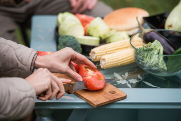 Joyful efforts to prepare for a family holiday in the yard. Hands of a man and a woman preparing vegetables for grilling for a picnic. Without a face