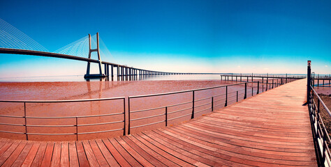 El puente Vasco da Gama sobre el río Tajo al atardecer con sol y nubes. Lisboa, Portugal. Fotografía callejera a color. Paisaje escénico y turismo