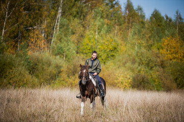 Cute girl-rider rides her fast horse on the territory of the ranch.