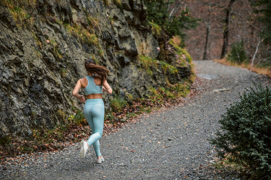 Young woman exercising while running on forest path