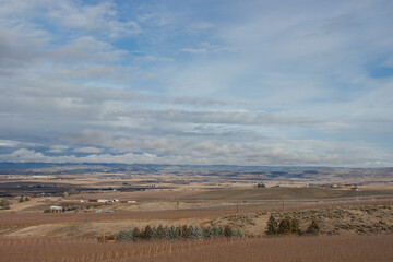Beautiful autumn landscape with mountains on the horizon, dry grass, trees, roads, gardens, and fields, unusual great blue sky with  fluffy light gray clouds