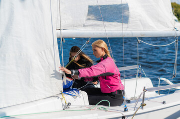 Two girls decided to spend a weekend on the river, preparing the yacht to go out on the water.