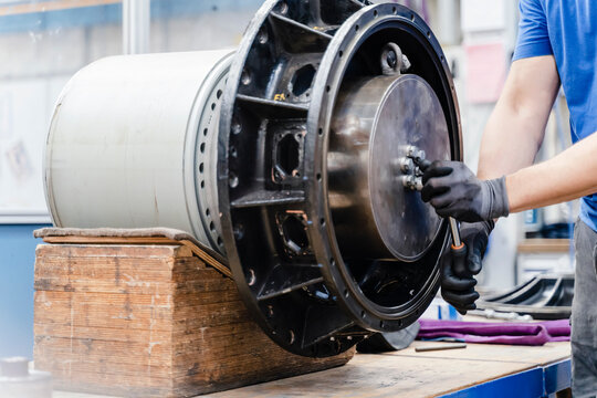 Hands of male engineer fastening bolt with wrench at industry