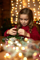 Obraz na płótnie Canvas happy cute little child girl makes a handmade Christmas wreath at home.