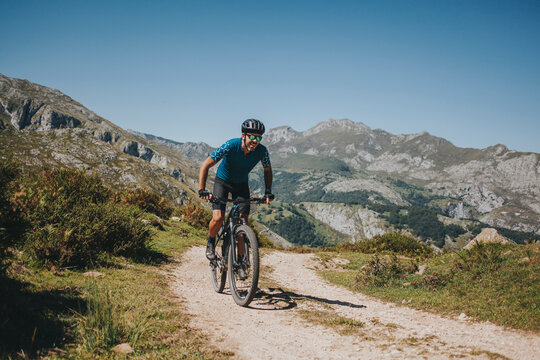 Male cyclist riding mountain bike on trail against sky, Picos de Europa National Park, Asturias, Spain