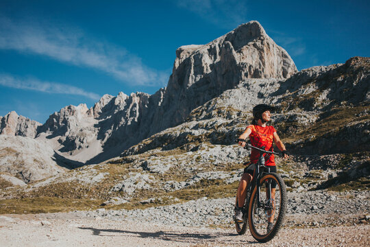 Female cyclist with bicycle at Picos de Europa National Park on sunny day, Cantabria, Spain