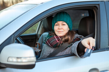 Female driver making cashless payment via credit card inside of her car, stretching hand through the window