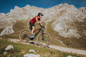 Female cyclist riding bike near rock mountain at Picos de Europa National Park, Cantabria, Spain