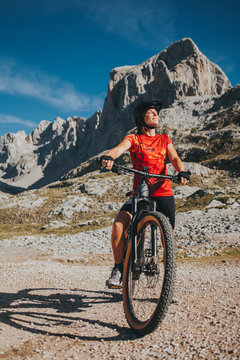 Smiling female cyclist with eyes closed on bicycle at Picos de Europa National Park, Cantabria, Spain