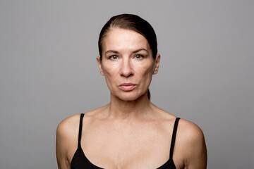 Mature woman with slicked back hair against gray background
