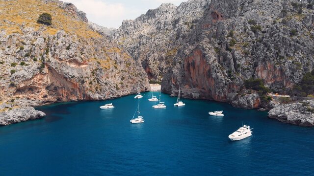 Serra De Tramuntana,Sa Calobra, Torrent De Pareis beach, aerial ,crystal clear water of mediterranean sea with moored sailing boats and yacht going towards the beach. High quality photo
