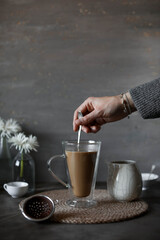 A woman's hand pours cream into the coffee. Pastel shades. Slow living.