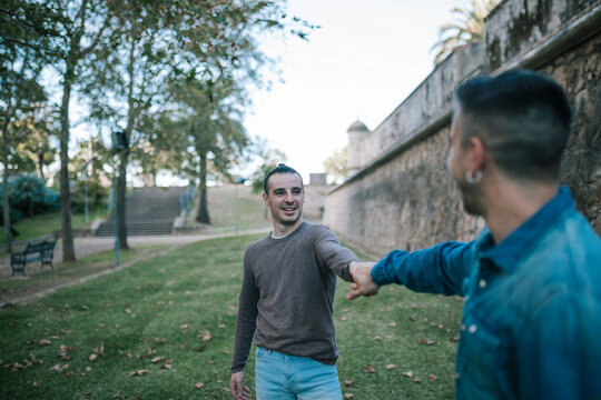 Man holding hand of boyfriend while standing at public park