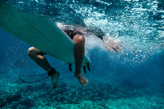 Male surfer sitting on surfboard while surfing in sea at Maldives