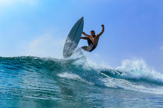 Man with surfboard surfing on sea wave against clear sky
