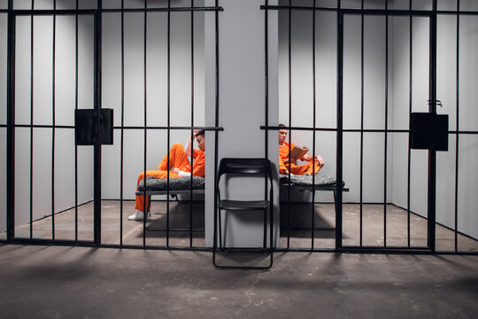 Prisoners in their cells are bored before lights out in prison. Read books. Symmetrical composition. Copy space.