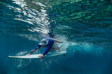 Male surfer diving with surfboard in sea at Maldives