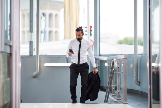 Businessman walking up stairs with smart phone in hand