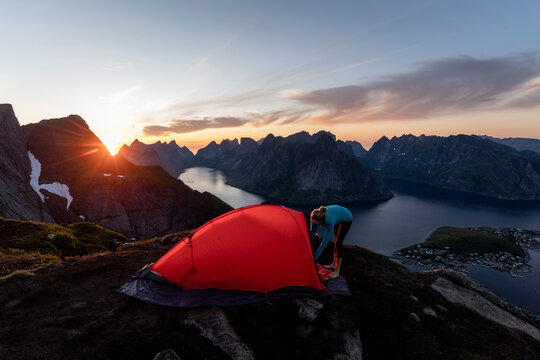 Mid adult woman building camp on mountain at Reinebringen. Lofoten, Norway