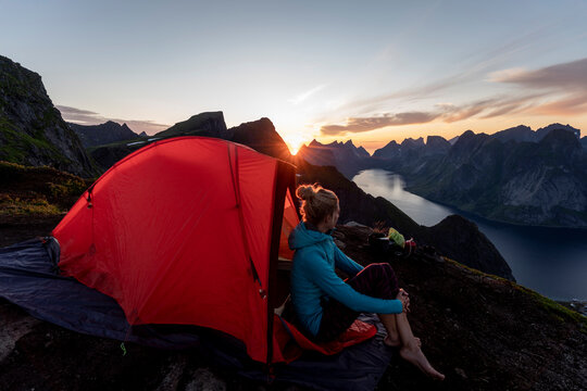 Woman admiring view while sitting in camp on mountain at Reinebringen. Lofoten, Norway