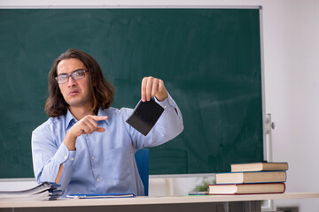 Young male teacher in front of green board