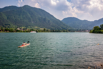 Active senior man kayaking on Lake Idro against cloudy sky