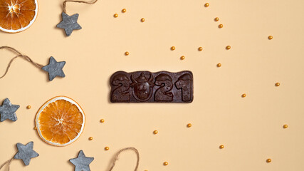Orange slices, wooden stars and cake sprinkles. Chocolate bar 2021. Top view.
