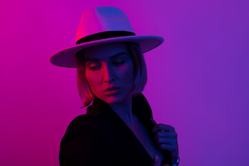Beauty portrait style glamor girl in hat. Closeup fashion portrait woman with copy space neon light and color filters lighting  