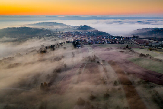 Germany, Baden-Wurttemberg, Berglen, Drone view of village shrouded in thick fog at dawn