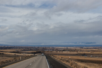 A beautiful landscape with a highway along which cars and trucks drive, on a sunny autumn day among the mountains, a blue sky with fluffy gray-blue clouds. Oregon, USA, 12-5-2019