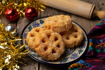 Mexican fritter with sugar and cinnamon called bunuelo on wooden background
