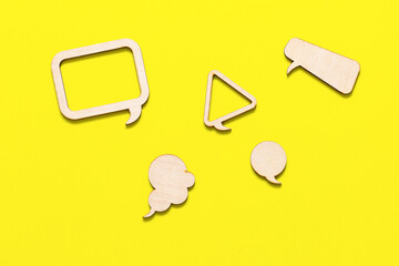 Figures made of wood in the form of callouts, on a yellow background. For ideas. A piece of wood in the form of a speech cloud. Yellow background.