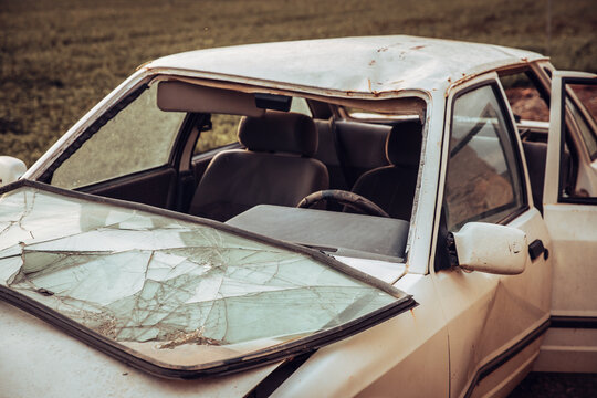 White wrecked car deteriorating outdoors