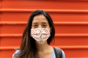 Contemplating woman with protective face mask standing against shutter during COVID-19