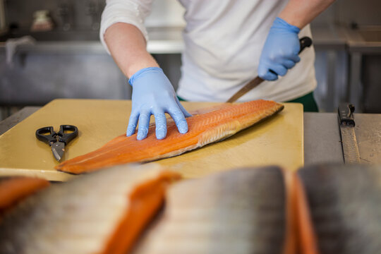 Man cutting fish at counter in food processing plant