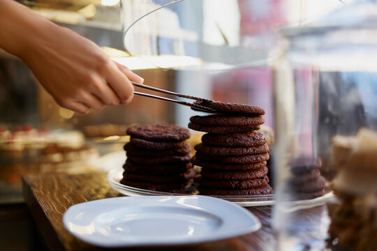 Hand of barista removing cookie biscuits while working at cafe