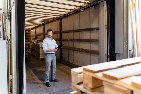 Inspector with digital tablet loading material while standing in delivery truck