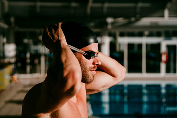 Handsome male swimmer preparing for swimming on sunny day