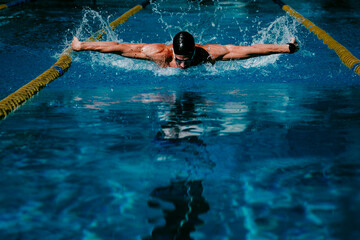 Professional male swimmer practicing butterfly stroke in swimming pool