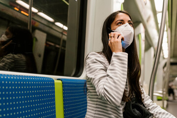 Woman looking away while talking on smart phone in metro train