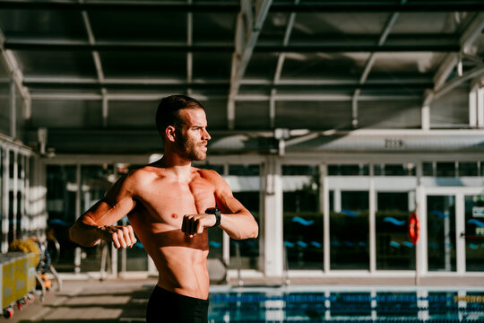 Shirtless male swimmer doing warm up exercise at poolside - Powered by Adobe