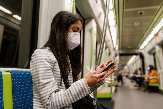 Female passenger text messaging through smart phone in metro train