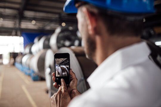 Businessman taking picture through smart phone in industry