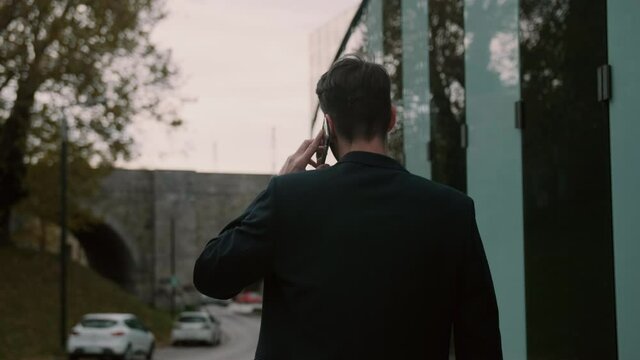 Businessman filming from behind walking and talking on the phone
