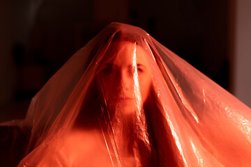 Worried woman covered in transparent plastic during pandemic