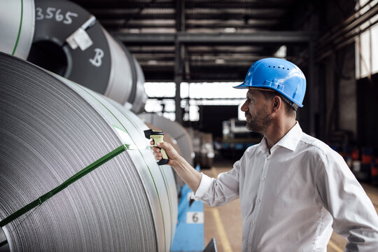 Man scanning barcode on steel rolls while standing in industry
