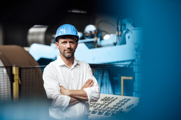 Businessman smiling with arms crossed at factory