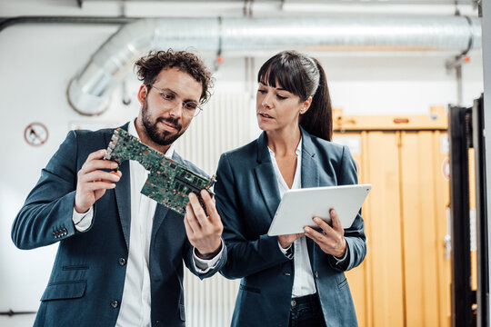 Business colleagues discussing while examining circuit board at industry